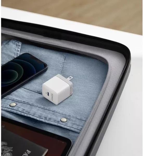 White USB-C adapter on a denim surface with a phone and tablet in the background