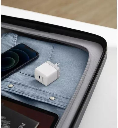 White USB-C adapter on a denim surface with a phone and tablet in the background